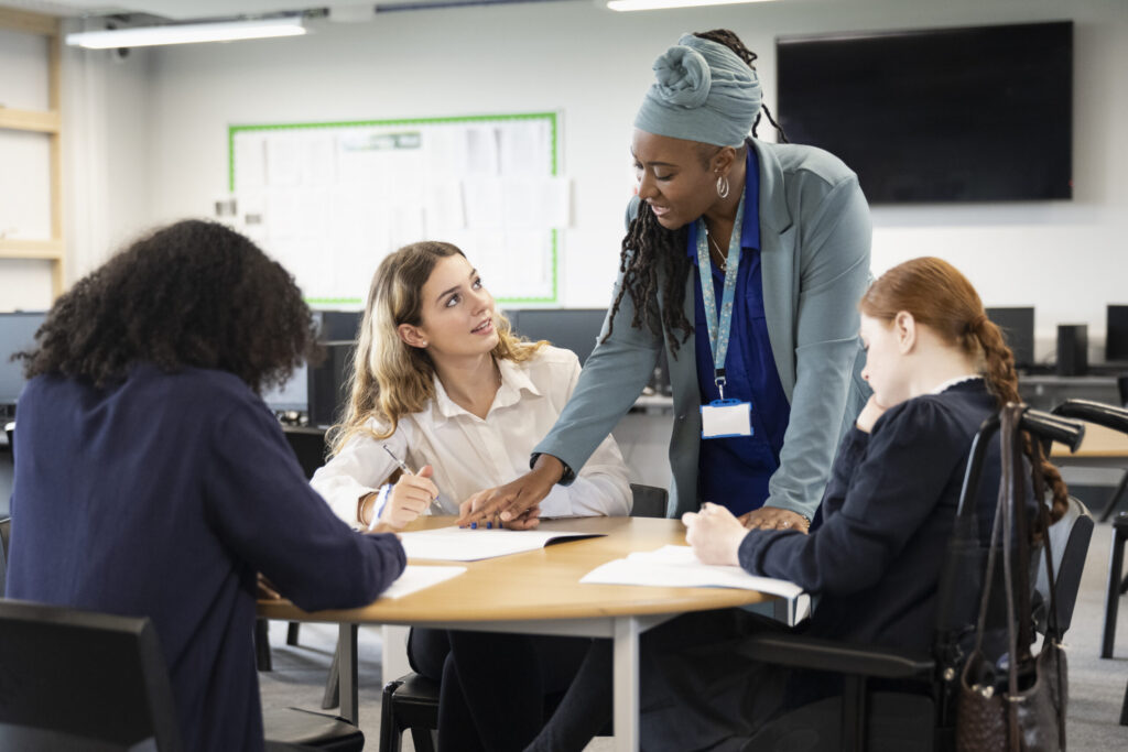 Female students working on assignment with help from teacher